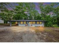 Charming single-story home with a covered parking area surrounded by mature trees and a gravel driveway at 8065 Highway 92 Dallas, Douglasville, GA 30134