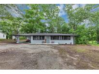 Charming one-story home featuring a carport and a covered porch, nestled in a serene, wooded setting at 8065 Highway 92 Dallas, Douglasville, GA 30134