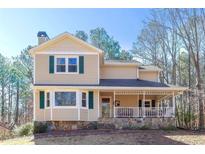 Charming two-story home with a welcoming front porch and a well-maintained yard, perfect for outdoor enjoyment at 165 Carriage Gate Dr, Sharpsburg, GA 30277