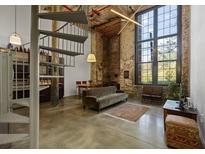 Loft living room boasts exposed brick, spiral staircase, a large window and industrial modern lighting fixture at 170 Boulevard Se # 104E, Atlanta, GA 30312