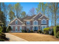 Charming two-story home with a well-manicured lawn, complemented by mature trees and classic architectural details at 315 Chandon Place Ct, Alpharetta, GA 30022