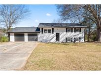 Charming two-story home featuring a two-car garage, black shutters, and a spacious front yard at 6650 Baldwin Ct, Riverdale, GA 30274