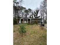 Modest one-story home with brick facade, covered front porch, and mature trees in the front yard at 4438 Ryan Rd, Conley, GA 30288