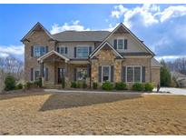 Stunning two-story brick home with stone accents, gray shutters, and a welcoming front porch at 5540 Wood Falls Dr, Buford, GA 30518