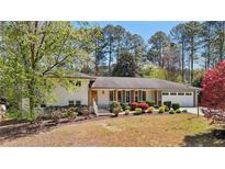 Charming home with mature landscaping, complemented by a white brick exterior and an attached two-car garage at 1541 High Haven Ne Ct, Atlanta, GA 30329
