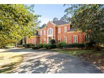 Stately brick home featuring a circular driveway, manicured landscaping, and bright red shutters at 440 Dix Lee On Dr., Fayetteville, GA 30215