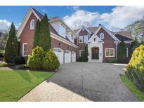Beautiful brick home featuring a three-car garage, manicured lawn, and a spacious driveway at 821 Camden Park Ct, Atlanta, GA 30342