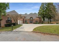 Stately brick home with a circular driveway, mature trees and three-car garage at 1483 Jones Rd, Roswell, GA 30075