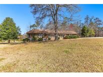 Charming single-story home with a well-maintained lawn and mature trees, set against a clear blue sky at 9095 Cedar Grove Rd, Fairburn, GA 30213