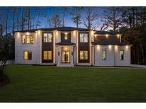 Elegant two-story home featuring a lush lawn, brick facade, dark trim, and inviting entryway at 942 Fairfield Dr, Marietta, GA 30068