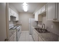 Galley kitchen featuring white cabinets, stone countertops, and matching white appliances at 37 Le Parc Fontaine, Lithonia, GA 30038