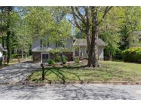 Charming split-level home featuring stone accents, a well-maintained lawn, and a mature shade tree at 8876 Ashwood Dr, Riverdale, GA 30274