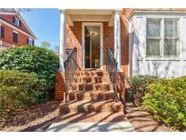 Inviting brick home entrance with white columns, black railings, and beautifully landscaped surroundings at 5210 Davenport Pl, Roswell, GA 30075