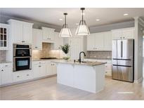 Bright kitchen with white cabinetry, stainless steel appliances, granite countertops and a large island at 5210 Davenport Pl, Roswell, GA 30075