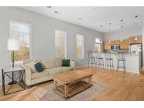 Bright living room with hardwood floors, sofa, area rug, large windows, and an open floorplan with the kitchen and breakfast bar at 1430 Dresden Ne Dr # 215, Atlanta, GA 30319