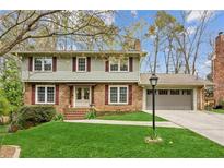 Charming two-story home with brick and siding, plus an attached two car garage, nestled on a lush green lawn at 4873 Parliament Way, Atlanta, GA 30338