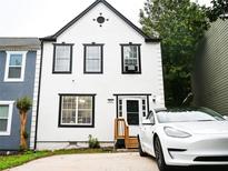 Charming home featuring a white facade with black trim and a modern white car in the driveway at 811 Heritage Valley Rd, Norcross, GA 30093