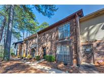 Charming two-story brick townhouse with shuttered windows, a black door, and mature trees at 748 Garden View Dr, Stone Mountain, GA 30083