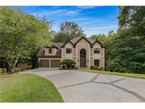 Elegant home featuring manicured landscaping, a two-car garage and brick accents on the driveway at 275 Tynebrae Pl, Roswell, GA 30075