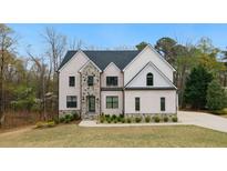 Elegant two-story home with white painted brick, stone accents, a manicured lawn and professional landscaping at 4980 Wildeoak Trl, Douglasville, GA 30135