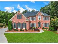 Charming brick home featuring a manicured lawn and lush landscaping, offering great curb appeal at 2930 Monticello Dr, Cumming, GA 30041