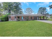 Charming brick home features a well-manicured lawn, attached carport, and inviting curb appeal at 2306 Ashleywoods Dr, Tucker, GA 30084