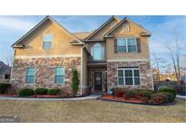 Charming two-story home featuring a stone and tan shingle facade and a well-manicured lawn with mature landscaping at 5143 Olive Branch Cir, Powder Springs, GA 30127