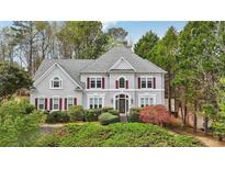Charming two-story home with a landscaped yard and gray siding surrounded by mature trees at 5300 Cottage Farm Rd, Johns Creek, GA 30022