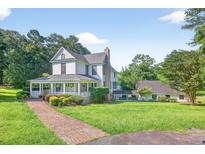 Charming two-story home featuring a welcoming wrap-around porch and meticulously landscaped front yard at 1768 Hood Rd, Dacula, GA 30019