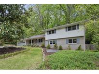 Charming two-story home with light gray brick and white siding nestled among mature trees at 205 Glencourtney Dr, Sandy Springs, GA 30328