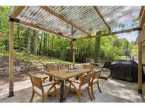 Covered patio area featuring a wood table with seating, a grill, and a lush green backdrop at 205 Glencourtney Dr, Sandy Springs, GA 30328