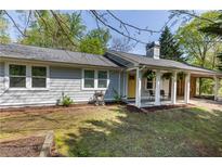 Charming home with a covered porch and yellow front door, surrounded by lush greenery and a well-maintained lawn at 5369 Blue Grass Ln, Sugar Hill, GA 30518