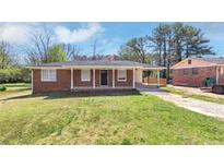Charming brick home featuring a covered front porch and a well-manicured lawn at 4338 Rob Roy Ln, Conley, GA 30288