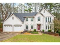 Charming two-story home with a well-manicured lawn, three-car garage, and attractive architectural details at 4057 Watkins Glen Dr, Woodstock, GA 30189