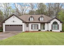 Charming white brick home featuring a well-manicured lawn, dormers, and a two-car garage at 5233 Hayden Farms Dr, Powder Springs, GA 30127