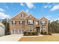 Charming two-story brick home featuring a two-car garage, manicured lawn, and beautifully landscaped front yard at 3478 Spring Place Ct, Loganville, GA 30052