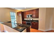 Well-lit kitchen features dark wood cabinets, stainless steel appliances and granite countertops at 5905 Brookside Oak Cir, Norcross, GA 30093