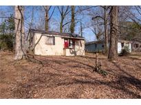 Charming single-story home with brick exterior and a red front door surrounded by a wooded lot at 2174 Clanton Ter, Decatur, GA 30034