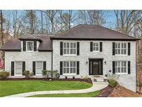 Well-manicured two-story white brick home with lush lawn and a charming walkway at 950 Ivy St, Cumming, GA 30041