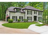 Charming two-story brick home with black shutters, lush lawn, and a curved driveway at 950 Ivy St, Cumming, GA 30041