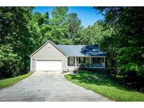 Charming home with a one-car garage and a stone-accented front porch nestled among mature trees at 3013 Rockview Dr, Loganville, GA 30052