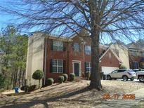 Charming two-story brick home with black shutters, a lawn with pruned bushes, and a driveway with parked cars at , College Park, GA 30349