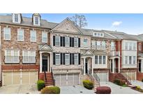 Beautiful townhome exterior featuring brick, stone accents, and symmetrical windows with black shutters at 2517 Ashwicke Se Dr, Atlanta, GA 30339