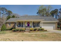 Inviting single-story home featuring a covered front porch, stone accents, and a charming purple front door at 802 Sugar Creek Se Dr, Conyers, GA 30094