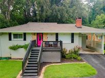 Charming single-story home with a brick chimney, pink door, and inviting front porch at 240 W Lake Nw Dr, Atlanta, GA 30314