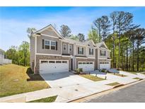 Three newly built townhomes featuring a brick facade, attached garages, and a well-manicured lawn at 1180 Cades Walk, Lawrenceville, GA 30045