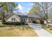 Charming home featuring a stone facade and a long driveway nestled amongst mature trees at 2019 Wiltshire Pl, Snellville, GA 30078