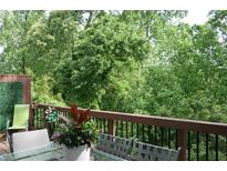 A relaxing outdoor space with a glass table, chairs, and lush greenery with trees visible from the wooden deck at 2022 Raven Way, Atlanta, GA 30341