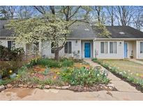 Charming townhouse with vibrant flower garden and a bright blue front door at 9023 Stoneleigh Trce, Douglasville, GA 30134