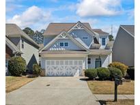 Charming two-story home with a light blue exterior, well-manicured landscaping, and a spacious two-car garage at 418 Belmont Way, Woodstock, GA 30189